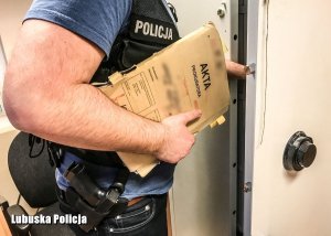 Sylwetka policjanta trzymającego w ręce teczkę z aktami