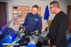 policjant pokazuje policyjny motocykl